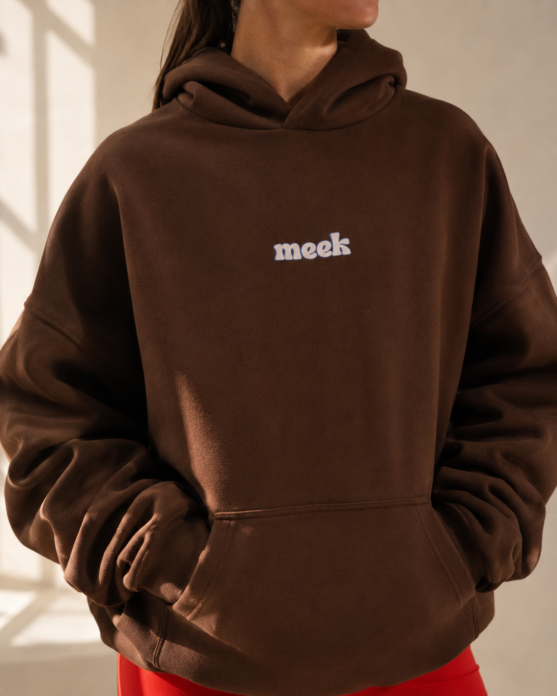 Female model posing wearing oversized Meek hoodie in coffee