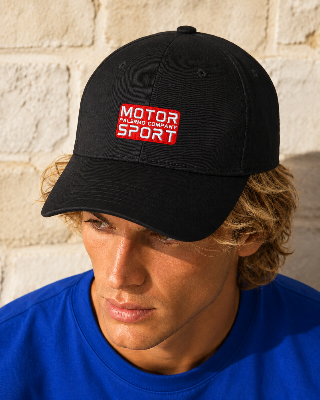 Man wears Palermo Company Motor Sport cap in black in outdoor Mediterranean setting