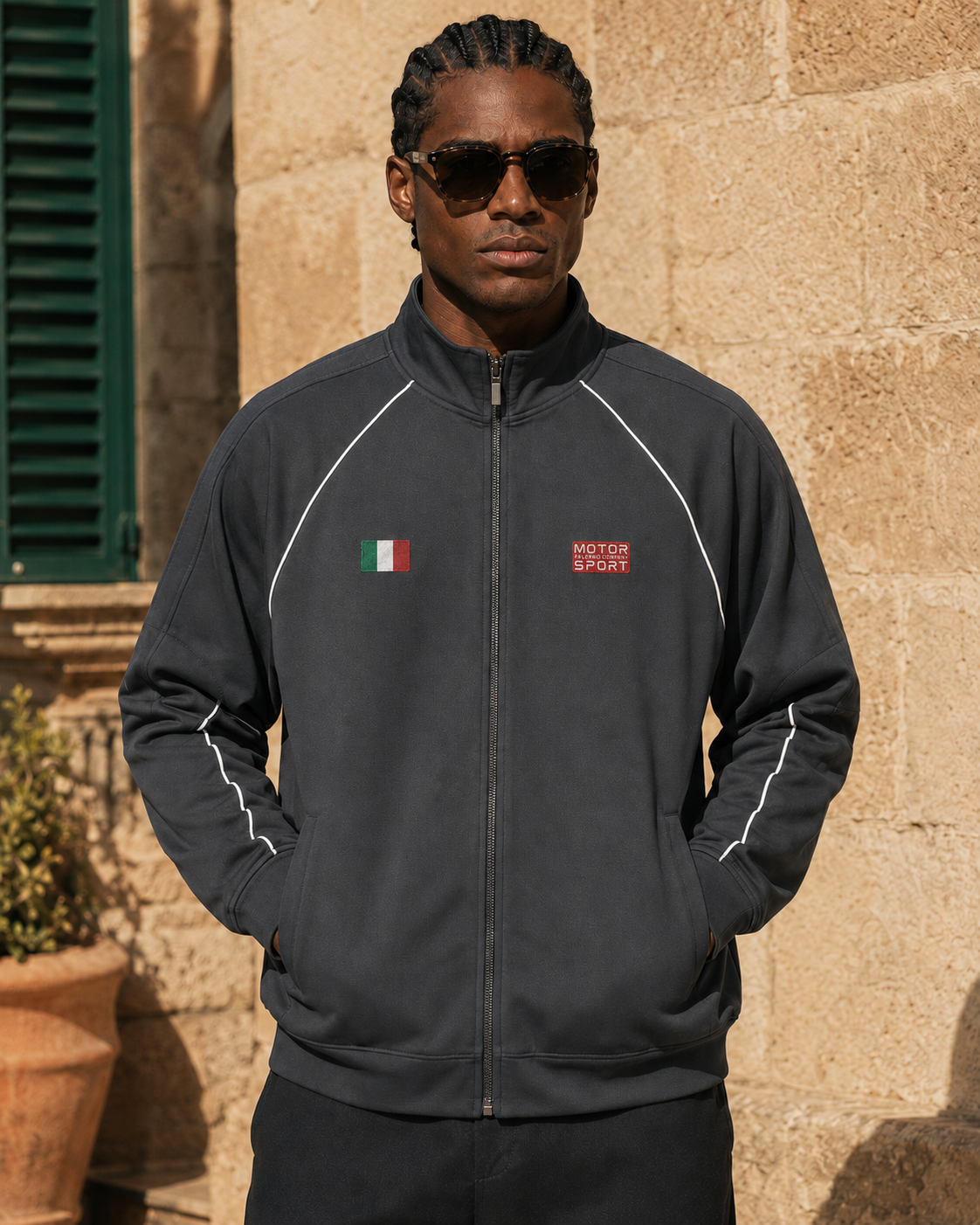 Model standing in front of cream coloured bricks wearing the Palermo Motor Sport Jacket in gray