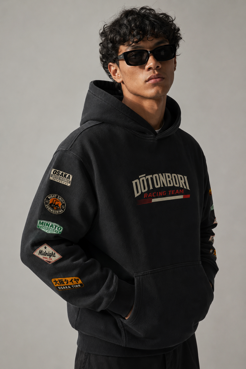 man wearing dotonbori racing team sponsor hoodie in well lit studio room