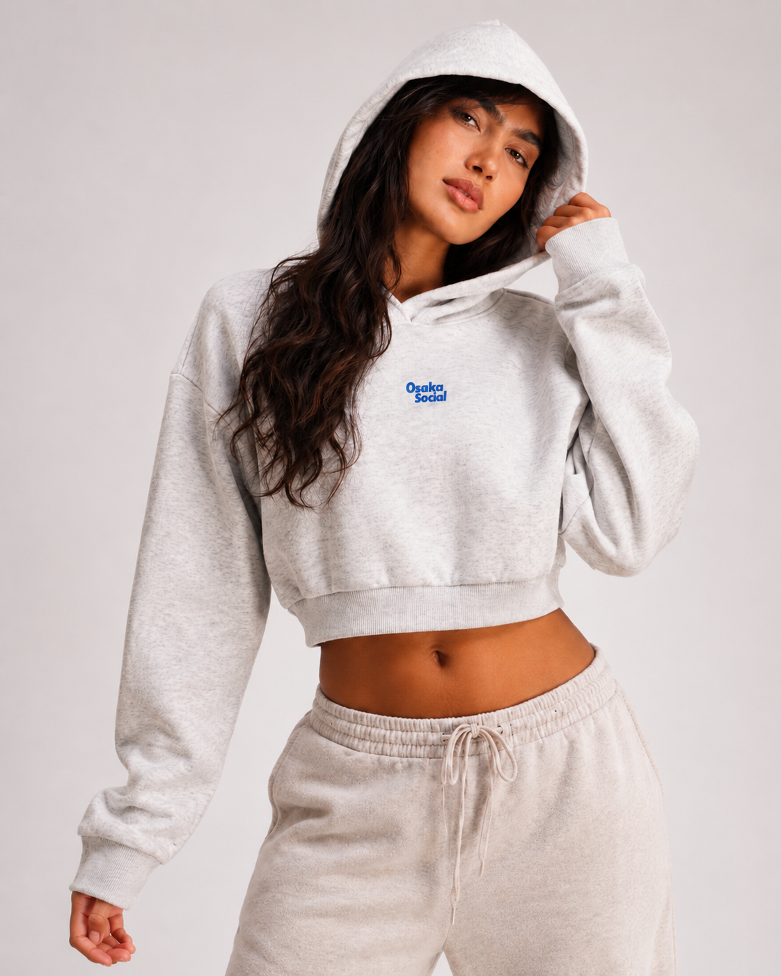 female model wearing osaka social cropped hoodie looking towards camera in well lit studio room